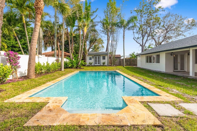 view of pool with a fenced in pool, a fenced backyard, an outbuilding, french doors, and a yard