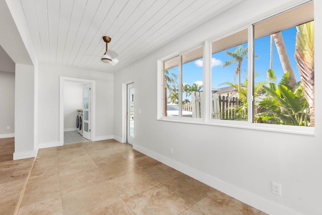 unfurnished room featuring light tile patterned flooring, washing machine and clothes dryer, wood ceiling, and baseboards