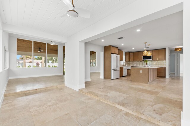 kitchen featuring brown cabinets, light countertops, freestanding refrigerator, a ceiling fan, and open floor plan