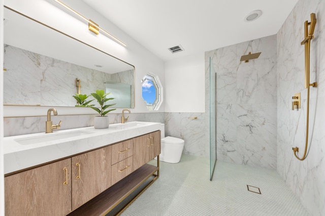 bathroom with vanity, a tile shower, tile walls, and toilet