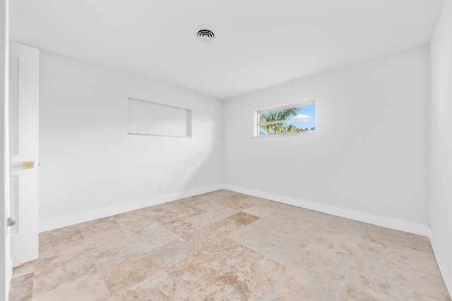 unfurnished room featuring baseboards and visible vents