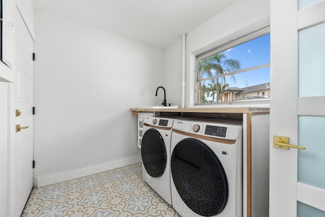 laundry area featuring baseboards, laundry area, a sink, and washer and dryer