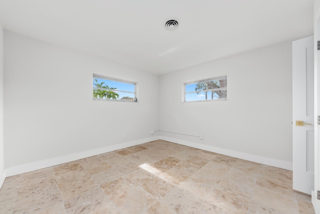 empty room with baseboards, stone finish floor, and visible vents