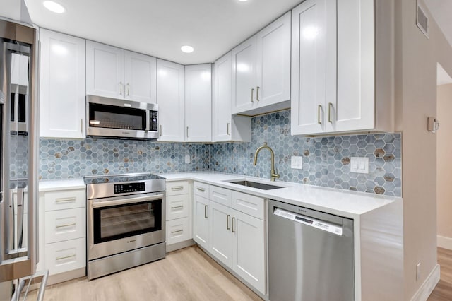 kitchen featuring visible vents, stainless steel appliances, light countertops, light wood-style floors, and a sink