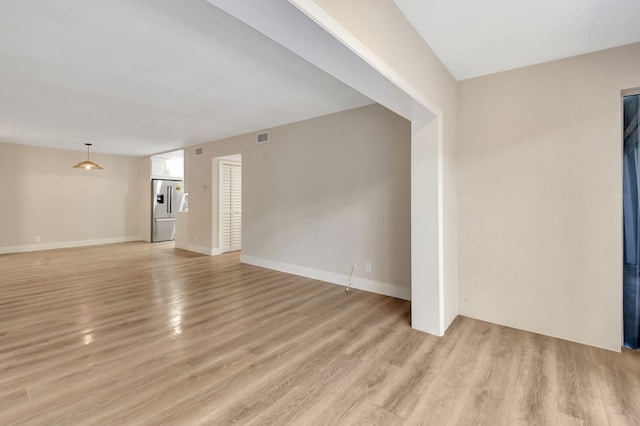 unfurnished living room featuring light wood-style flooring, visible vents, and baseboards