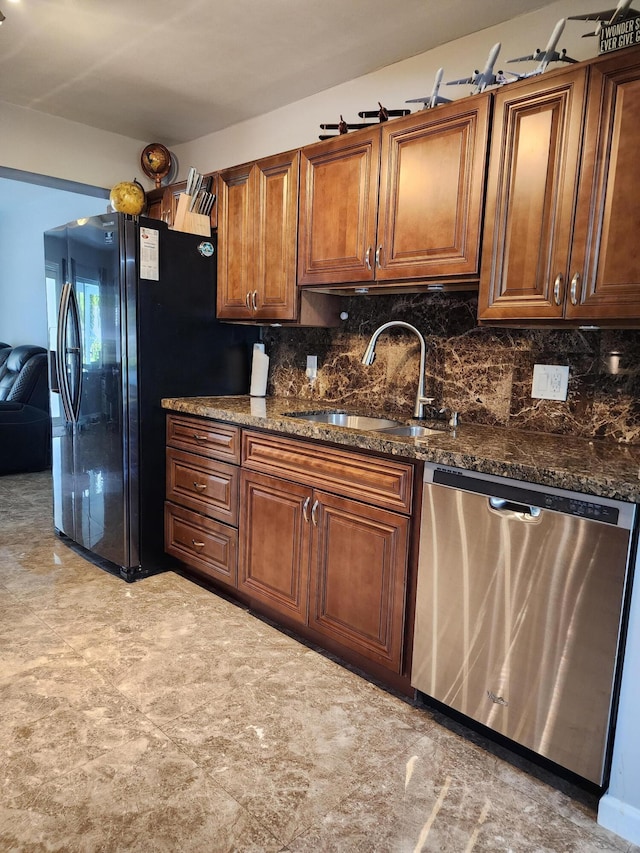 kitchen with stainless steel dishwasher, sink, and dark stone countertops