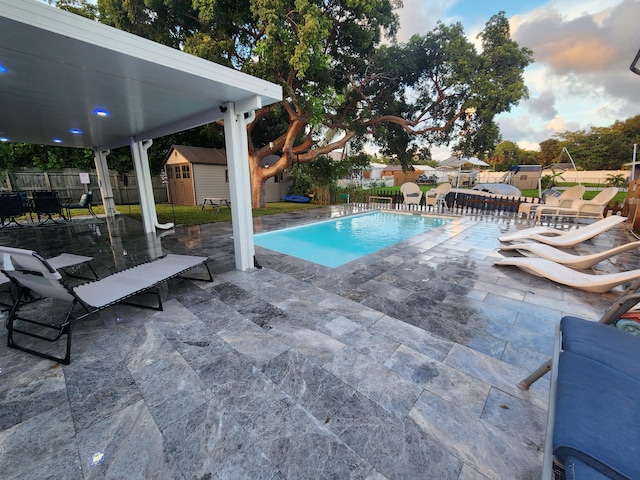 view of swimming pool with a patio and a shed