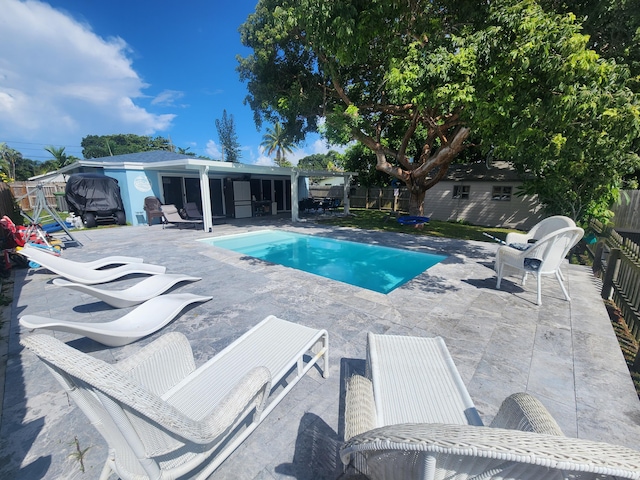 view of swimming pool featuring a patio and an outbuilding