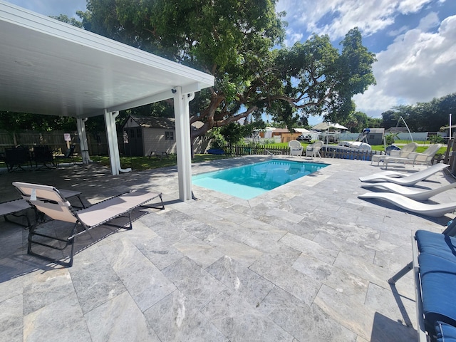 view of swimming pool featuring a storage shed, a diving board, and a patio