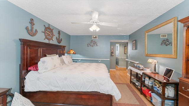 bedroom featuring ceiling fan, light hardwood / wood-style flooring, and a textured ceiling