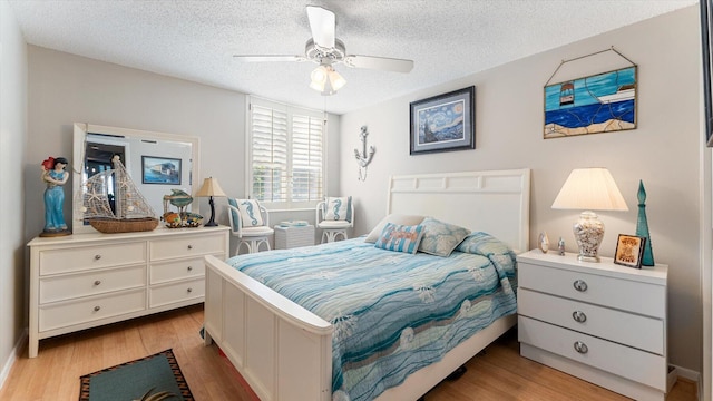 bedroom with ceiling fan, a textured ceiling, and light wood-type flooring