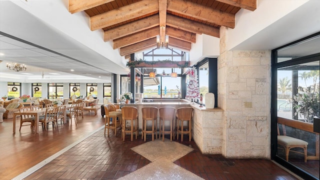 bar featuring high vaulted ceiling, beamed ceiling, wooden ceiling, and a chandelier