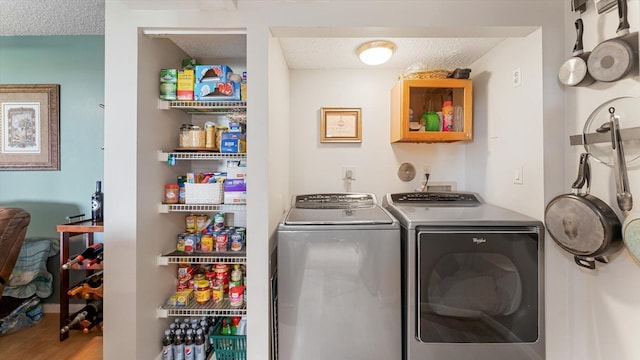 laundry room with washing machine and clothes dryer, wood-type flooring, and a textured ceiling