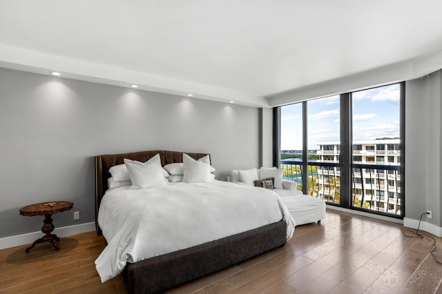 bedroom with expansive windows, access to outside, and hardwood / wood-style flooring