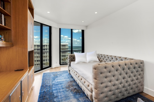 bedroom featuring floor to ceiling windows, access to exterior, and light wood-type flooring