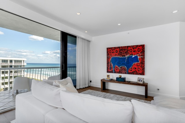 living room featuring hardwood / wood-style flooring, a water view, and a beach view