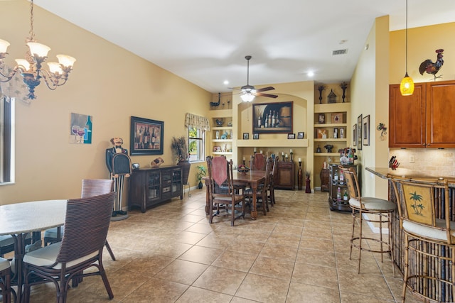 tiled dining space with ceiling fan with notable chandelier and built in features