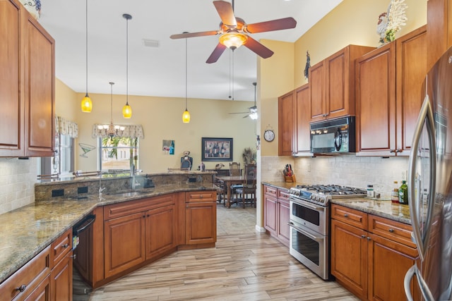 kitchen with sink, dark stone countertops, backsplash, hanging light fixtures, and black appliances