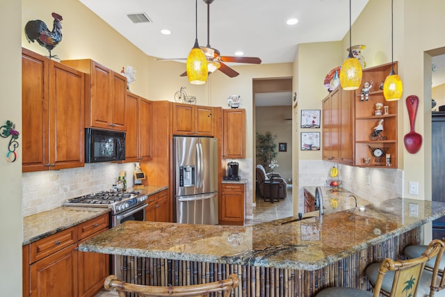 kitchen with pendant lighting, stainless steel fridge, a kitchen bar, kitchen peninsula, and light stone countertops