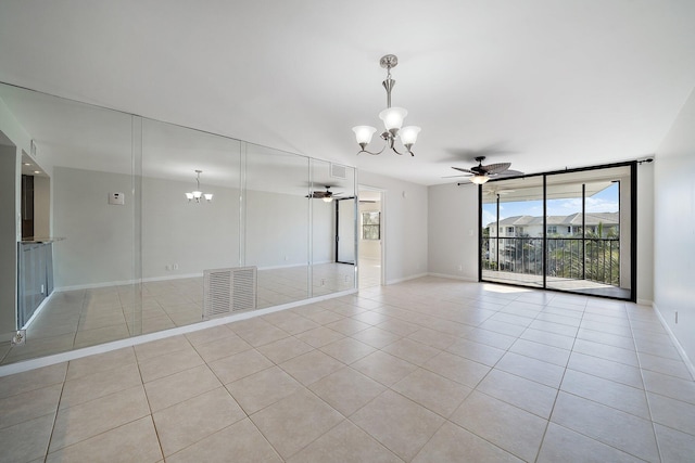 spare room with floor to ceiling windows, ceiling fan with notable chandelier, and light tile patterned floors