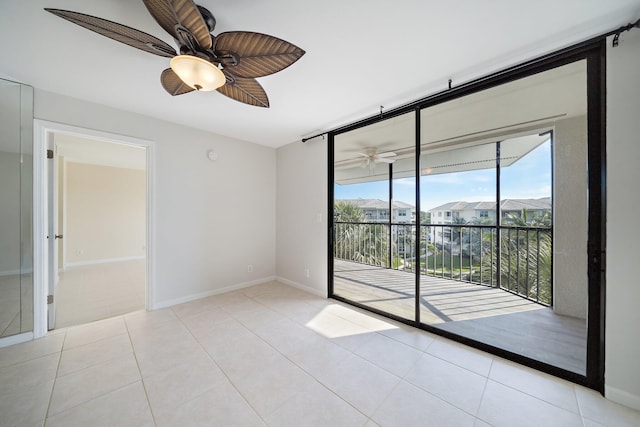 empty room with a wall of windows, ceiling fan, and light tile patterned flooring