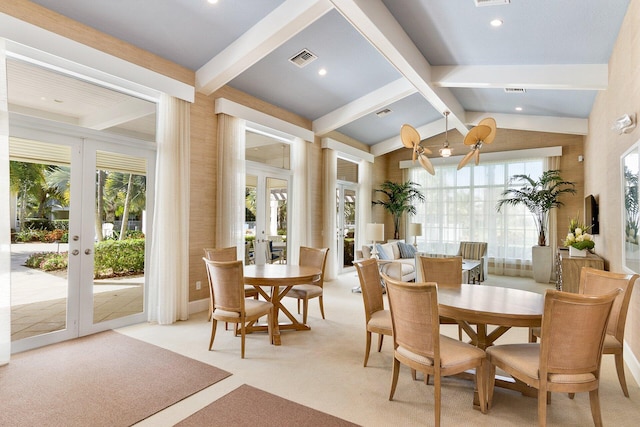 carpeted dining room featuring lofted ceiling with beams, a wealth of natural light, and french doors