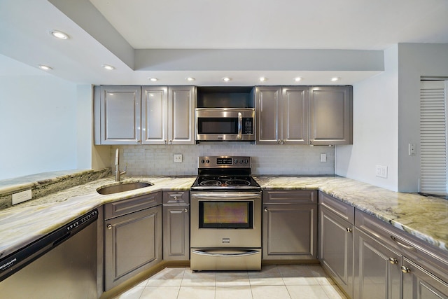 kitchen featuring appliances with stainless steel finishes, light stone countertops, sink, and decorative backsplash