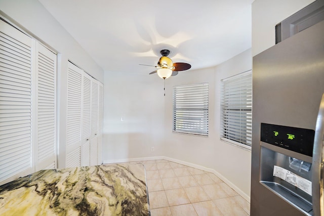 tiled bedroom with multiple closets, ceiling fan, and stainless steel fridge