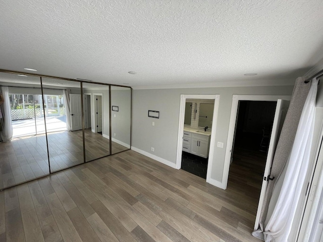 unfurnished bedroom with sink, crown molding, hardwood / wood-style flooring, access to exterior, and a textured ceiling