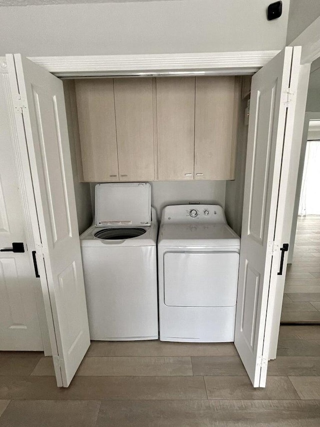 laundry area featuring hardwood / wood-style flooring, cabinets, and washing machine and dryer