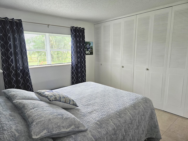 bedroom with light tile patterned floors, a textured ceiling, and a closet