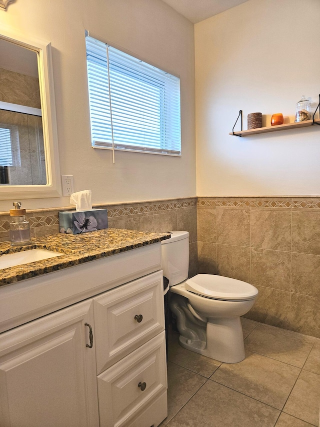 bathroom featuring tile patterned floors, vanity, toilet, and tile walls