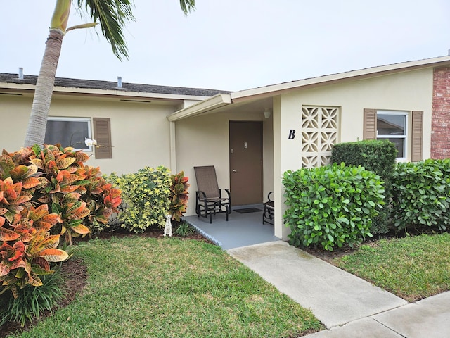 entrance to property with a patio and a lawn