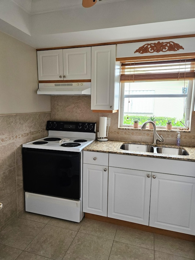 kitchen with range with electric cooktop, white cabinetry, sink, tile walls, and light tile patterned floors