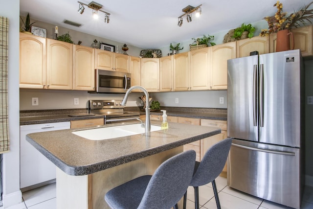 kitchen with appliances with stainless steel finishes, a kitchen island with sink, a breakfast bar area, and sink