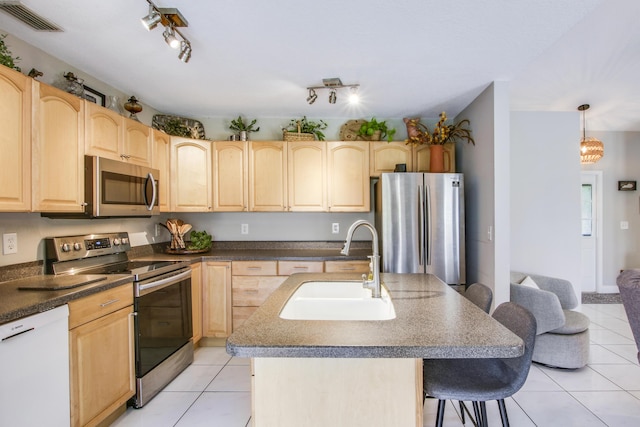 kitchen with sink, a center island with sink, light brown cabinets, and appliances with stainless steel finishes