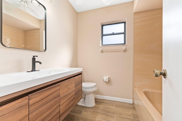 full bathroom featuring vanity, tiled shower / bath, and toilet