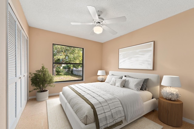 carpeted bedroom featuring ceiling fan, a closet, and a textured ceiling