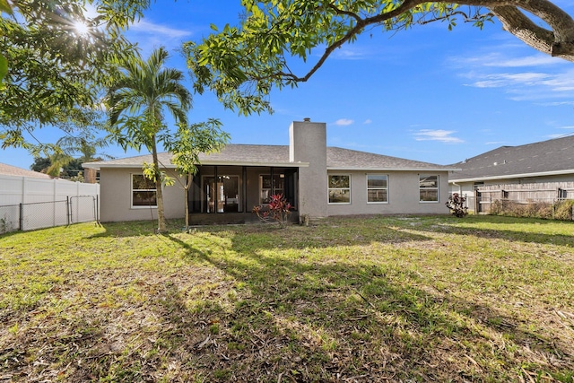 back of property with a sunroom and a yard