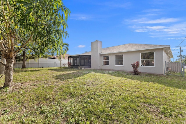 rear view of house with a yard and a sunroom