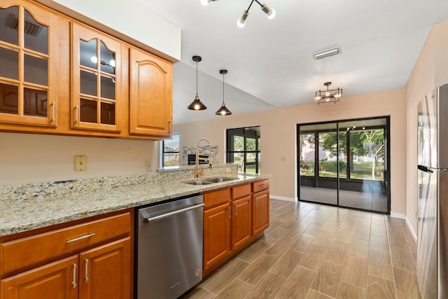 kitchen featuring sink, light stone counters, hanging light fixtures, light wood-type flooring, and appliances with stainless steel finishes