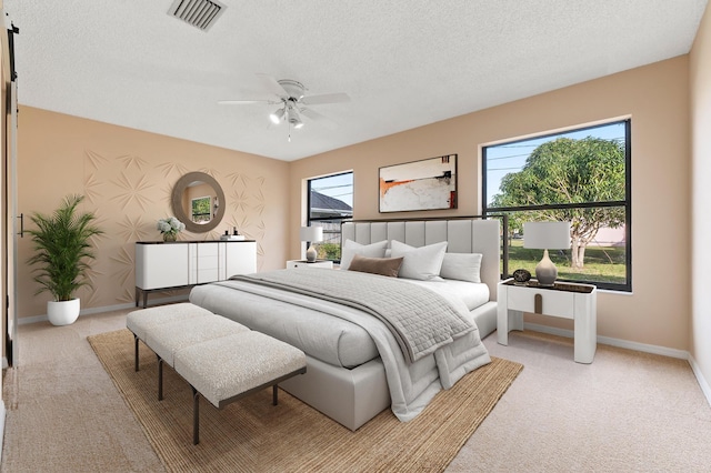 carpeted bedroom featuring ceiling fan and a textured ceiling