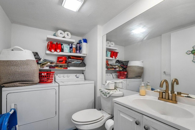 bathroom featuring vanity, a textured ceiling, washing machine and dryer, and toilet