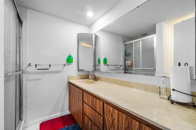 bathroom featuring vanity, an enclosed shower, and a textured ceiling