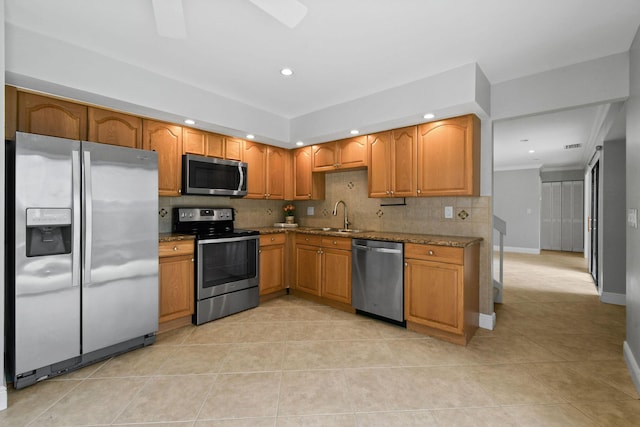 kitchen featuring appliances with stainless steel finishes, stone countertops, light tile patterned floors, and decorative backsplash