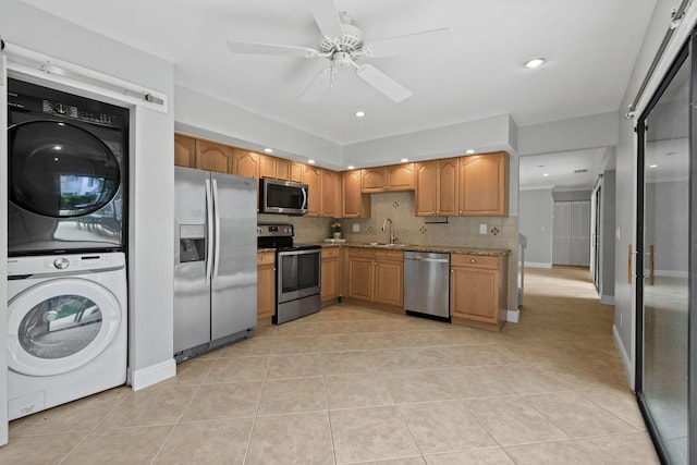 kitchen featuring ceiling fan, stacked washing maching and dryer, stainless steel appliances, tasteful backsplash, and light tile patterned flooring