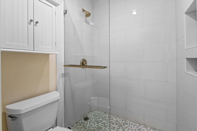 bathroom featuring a shower with shower door and toilet