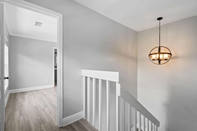 stairs with hardwood / wood-style floors and a chandelier