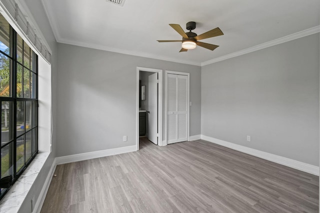 unfurnished bedroom with crown molding, ensuite bath, a closet, ceiling fan, and light hardwood / wood-style floors