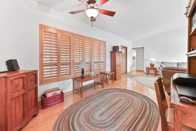 living area with vaulted ceiling, ceiling fan, and light hardwood / wood-style floors